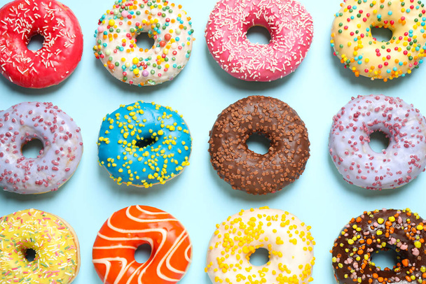 Delicious glazed donuts on light blue background, flat lay - Foto, Imagen