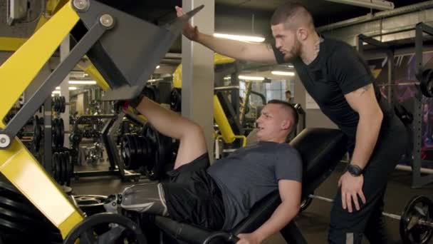 Hombre joven con prótesis de pierna usando máquina de prensa de piernas en el gimnasio
 - Imágenes, Vídeo
