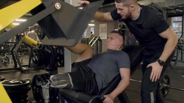 Młody człowiek z protezą nogi za pomocą prasy do nóg w siłowni - Materiał filmowy, wideo