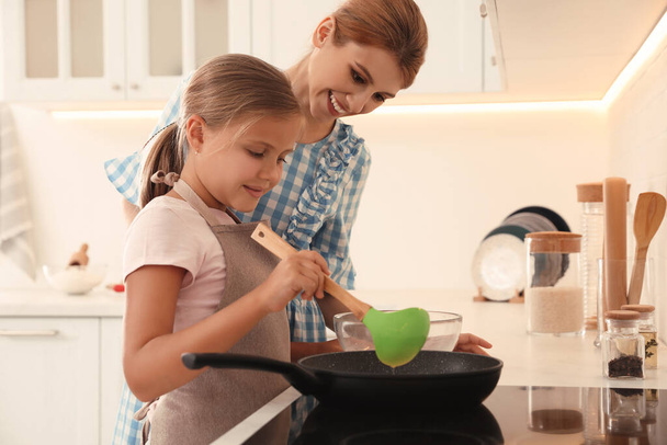 Mother and daughter making pancakes together in kitchen - Valokuva, kuva