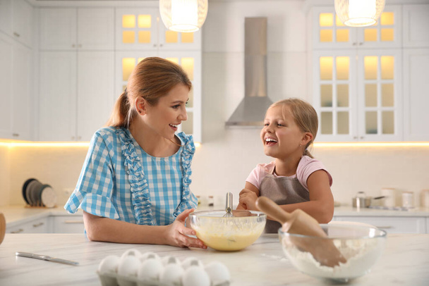 Mother and daughter making dough together in kitchen - Фото, изображение