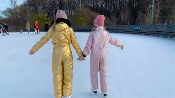 Urocze dziewczynki, jazda na łyżwach na lodowisku - Materiał filmowy, wideo