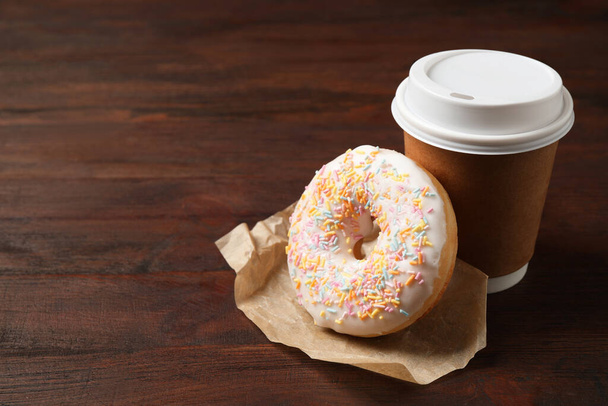 Yummy donut and paper cup on wooden table, space for text - Foto, Bild