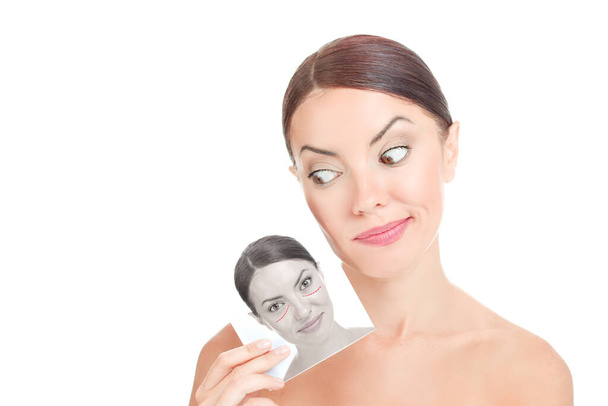Przed-po blepharoplastyce zabiegu kosmetycznego piękna. Zbliżenie sceptyczna kobieta ze świeżą, czystą twarzą trzyma zdesperowany obraz zmarszczonych oczu, twarz przed operacją plastyczną powiek na białym - Zdjęcie, obraz