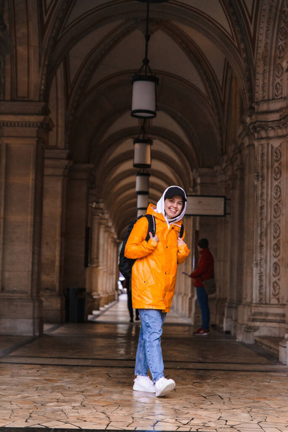 femme randonnée touristique avec sac à dos en imperméable jaune ville tourisme copie espace - Photo, image
