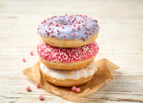 Delicious glazed donuts on white wooden table - Foto, Bild