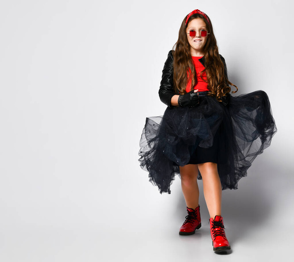 Young positive plus size girl model in bright rock style clothing, red boots and square glasses dtanding and feeling excited - 写真・画像