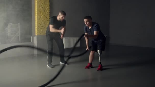 Mladý muž s protézou nohy pomocí bojových lan v tělocvičně - Záběry, video