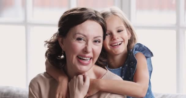 Cute happy small granddaughter embrace smiling mature grandma, portrait - Filmagem, Vídeo