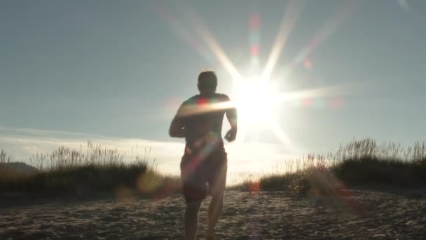 Henkilö juoksemassa hiekkadyyniä Oregonin rannikolla kauniina aurinkoisena päivänä
. - Materiaali, video