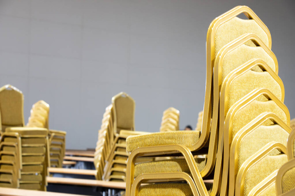 Stack Steel tuoli Kangas istuin pad keltainen kullan väri ja pöytä järjestää rivillä valmis perustamaan iso kokous, konferenssi, liike, työpaja, gaalaillallinen, häät seremonia Convention Hall of Hotel
 - Valokuva, kuva