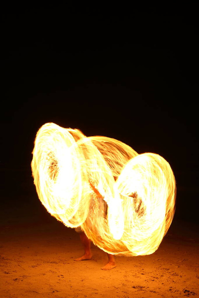High Skill Man παίζοντας πυροτεχνήματα γυρίζοντας ξύλινο κοντάρι με πετρέλαιο και φωτιά, κύκλο γύρω ως δαχτυλίδι της φωτιάς στην παραλία κατά μήκος του ωκεανού στο τροπικό νησί, μεγάλη κίνηση θόλωμα έκθεση - Φωτογραφία, εικόνα
