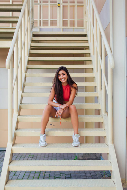 Street fashion summer portrait of a women on stairs outdoors. Full-length portrait young beautiful model in shorts posing on the stairs. - Fotoğraf, Görsel