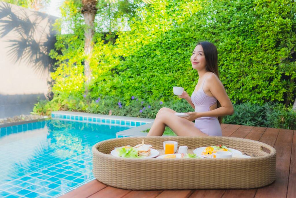 Muotokuva nuori aasialainen nainen onnellinen hymy nauttia kelluva aamiainen tarjotin uima-allas hotelli keinona - Valokuva, kuva