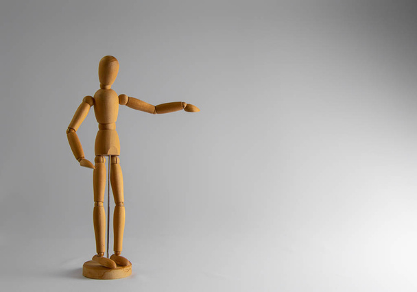 Wooden dummy stands on white background with hand raised - Zdjęcie, obraz
