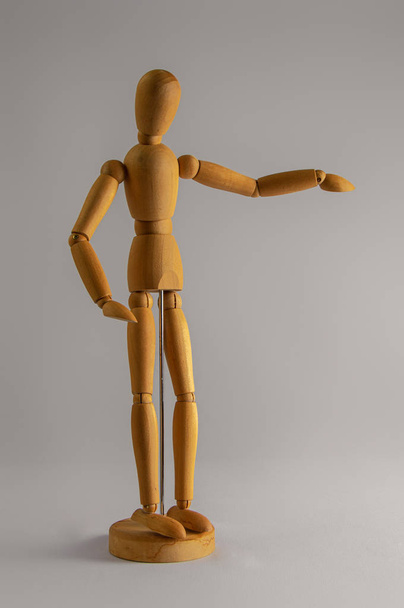 Wooden dummy stands on white background with hand raised - Foto, Bild