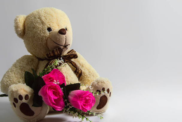 teddy bear with bouquet of artificial pink roses on white background - Foto, Bild