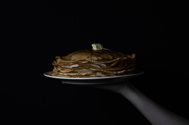 黒の背景に白い皿の上にバターをかけたパンケーキ - 写真・画像