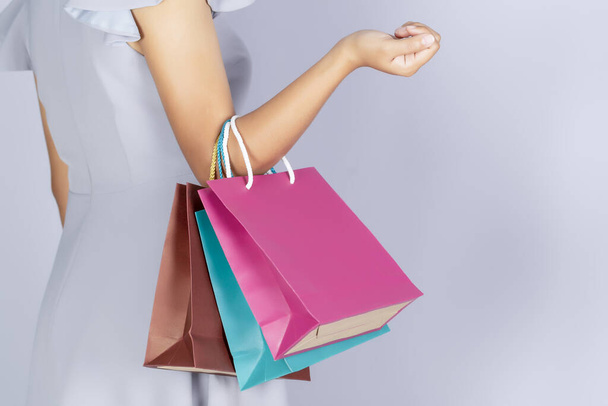 Female holding multicolored shopping bags on gray background. - Φωτογραφία, εικόνα