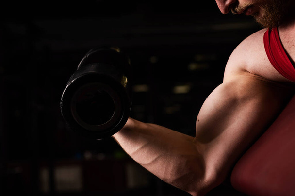 Unrecognizable man doing biceps exercise in the gym. Muscular man is engaged in bodybuilding. Close-up of male hands. - Foto, Bild