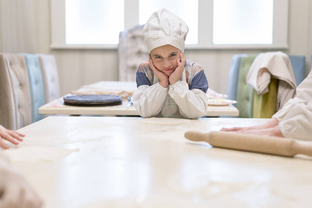 Aşçı çocuk mutfakta ev yapımı pizza hazırlıyor.. - Fotoğraf, Görsel