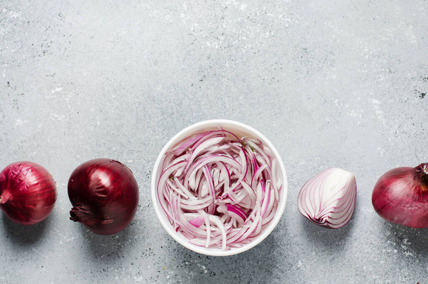 Pickled chopped red onion in vinegar in a white plate. Whole and sliced onions. A delicious side dish for meat and fish dishes. Light grey background. Flat top view - Valokuva, kuva