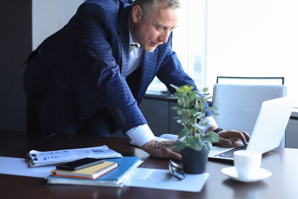 Elegant mature businessman analyzing data while working in office - Valokuva, kuva