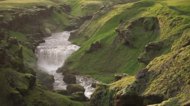 Slow motion of the beautiful smooth river in Iceland surrounded by green hills during the sunset on the Fimmvorduhals hiking trail close to Skogar - Felvétel, videó