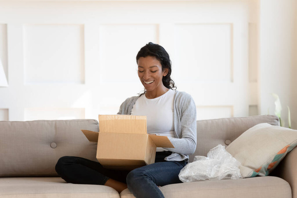 Happy biracial woman feel excited unpacking order - 写真・画像