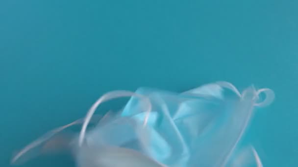 Blue surgical protective masks on a blue background. Coronavirus (COVID-19) hysteria is leading to mass mask shortages in the beginning of 2020. - Filmagem, Vídeo