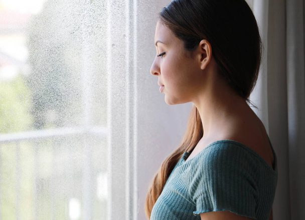 Melancholisch traurige Frau mit tiefem Blick zu Hause an einem regnerischen Tag, Fokus auf die Modelaugen, Indoor-Foto - Foto, Bild