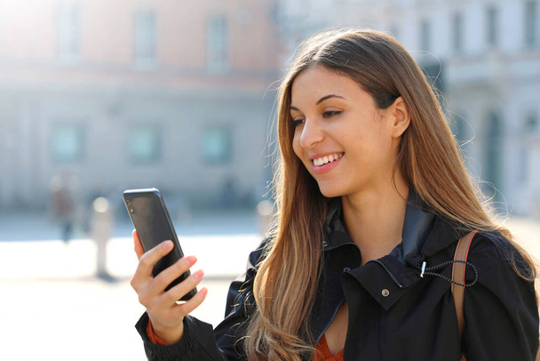 Videoanruf. Schöne Studentin macht Videoanruf mit ihrem Smartphone in der City Street. - Foto, Bild