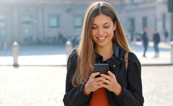 Felice studente ragazza in cerca di informazioni su smart phone in piedi in strada della città
 - Foto, immagini