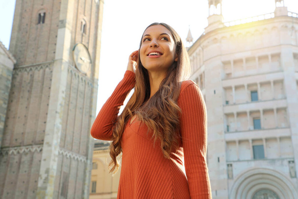Πορτρέτο της όμορφης τουρίστριας στην Πάρμα με τον καθεδρικό ναό Bell Tower και Βαπτιστήριο στο παρασκήνιο. Κορίτσι με ορόσημο Πάρμα στην Ιταλία. Χαμηλή γωνία βολής. - Φωτογραφία, εικόνα