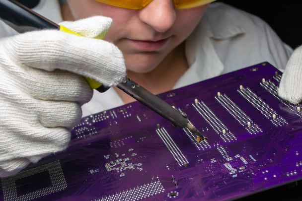Woman master solders a motherboard with a soldering iron - Photo, Image