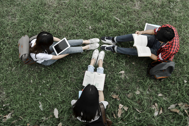 Universiteitsstudenten lezen een boek op het groene gras. - Foto, afbeelding