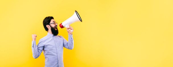 cheerful man shouting into megaphone over yellow background, success concept, panoramic mock-up - Photo, Image