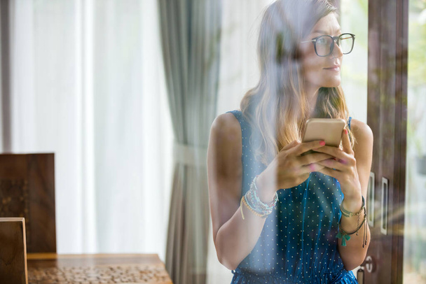 Mladá dospělá žena používající smartphone v moderním domě. - Fotografie, Obrázek