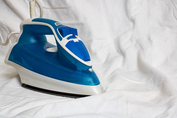 Blue iron on a white sheet, ironing, copy space - Photo, Image