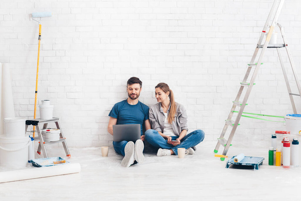Young couple using laptop during home improvement - Foto, imagen