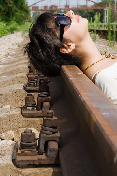Girl laying on the railroad carelessly - 写真・画像