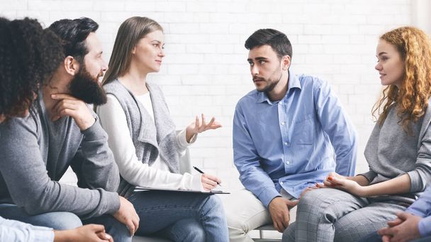 Психолог-наставник беседует с членами группы на сеансе терапии
 - Фото, изображение