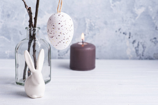 Huevo blanco y conejito en composición rústica de Pascua sobre mesa de madera blanca. Decoración en estilo escandinavo para tarjeta de felicitación con espacio para copias
 - Foto, Imagen