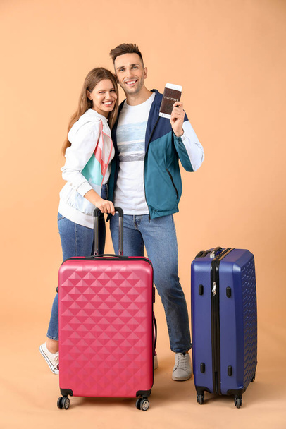 Couple of young tourists with luggage on color background - Фото, изображение