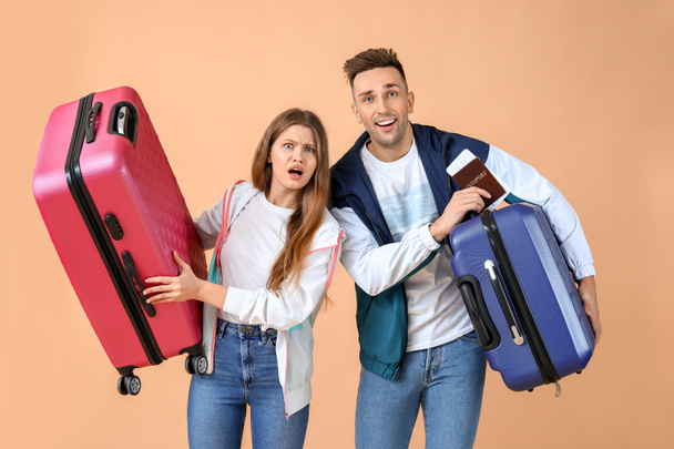 Emocionální pár mladých turistů se zavazadly na barevném pozadí - Fotografie, Obrázek