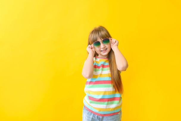 Funny little girl with sunglasses on color background - Photo, Image