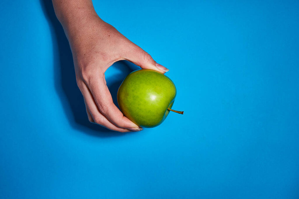 Zitrone in der Hand auf blauem Hintergrund. Flache Lage, Draufsicht, Kopierraum. Ernährungskonzept. - Foto, Bild