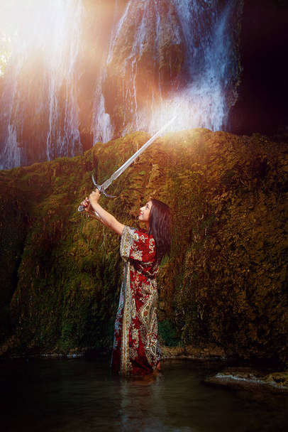 Žena s mečem v jezeře u vodopádu. - Fotografie, Obrázek