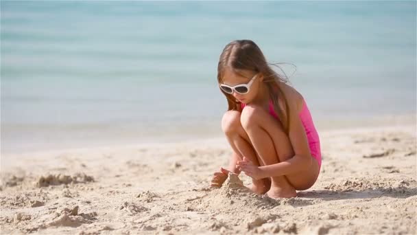 Malá dívka na tropické bílé pláži tvorby písku hrad - Záběry, video