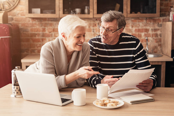 Feliz pareja de ancianos Planificación Presupuesto familiar junto con el ordenador portátil y los papeles
 - Foto, Imagen